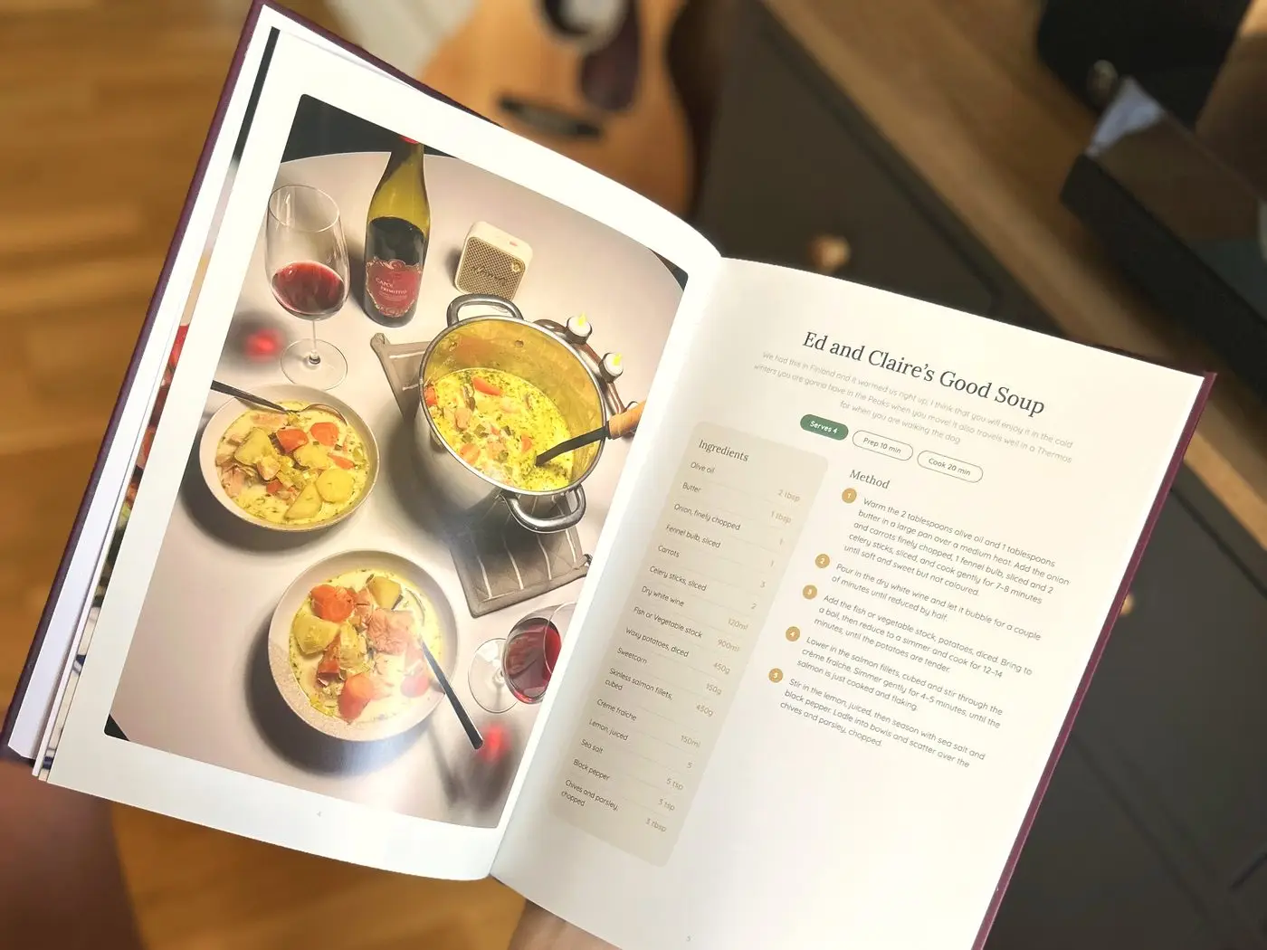 An open wedding cookbook showing a soup recipe beside a full-page photo of the dish laid out for a dinner party